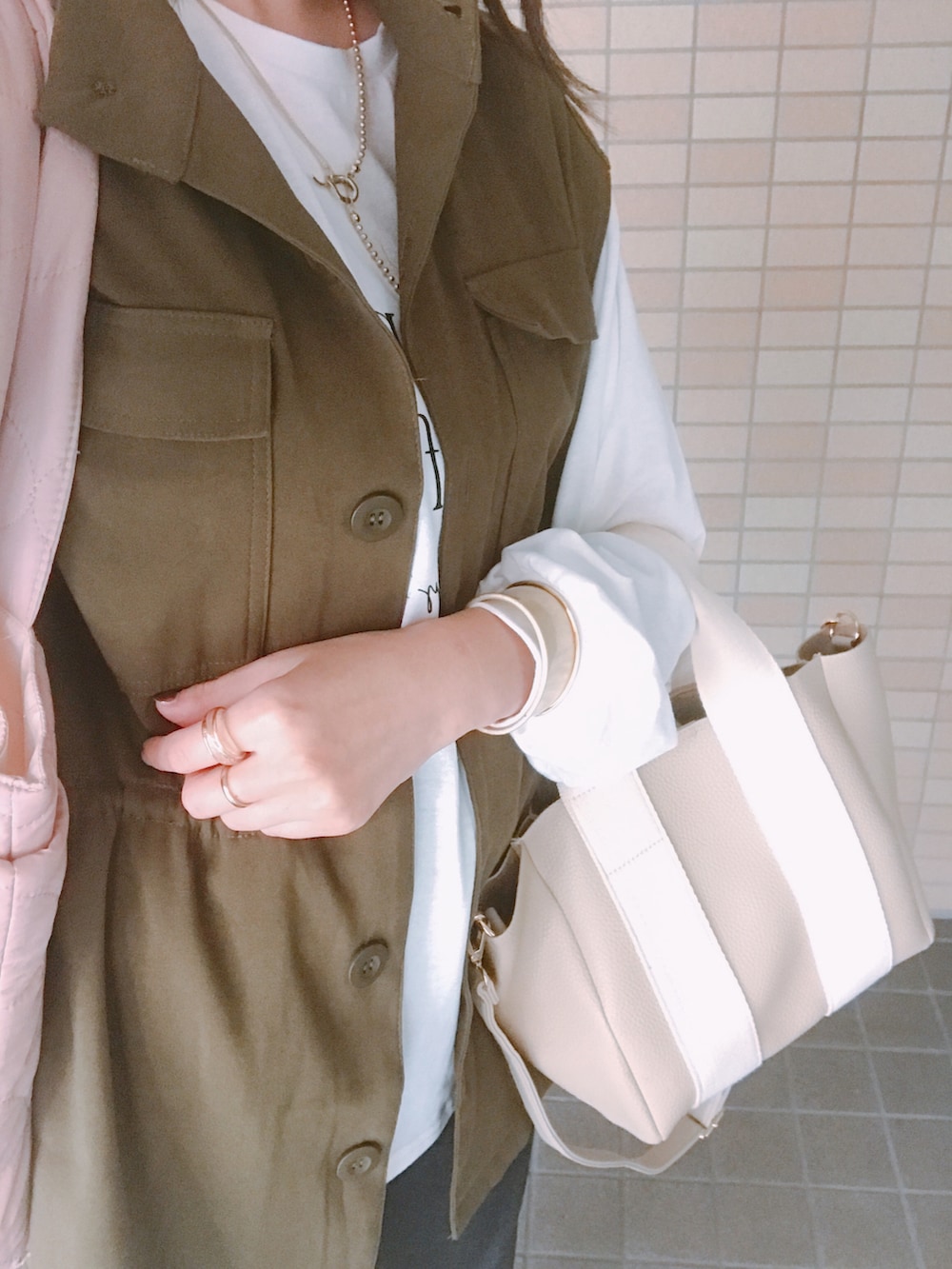 グリーン系のベスト、ホワイト系のTシャツ/カットソー、ゴールド系のネックレスを着用したレディースの秋コーディネートの3枚目の写真