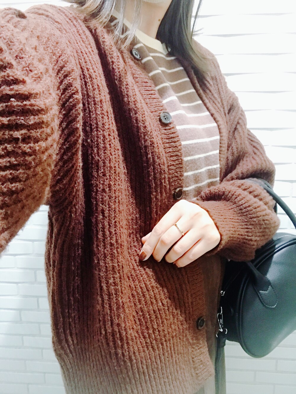 ホワイト系のハンドバッグ、ブラック系のボストンバッグ、ブラック系のブーツを着用したレディースの秋コーディネートの2枚目の写真