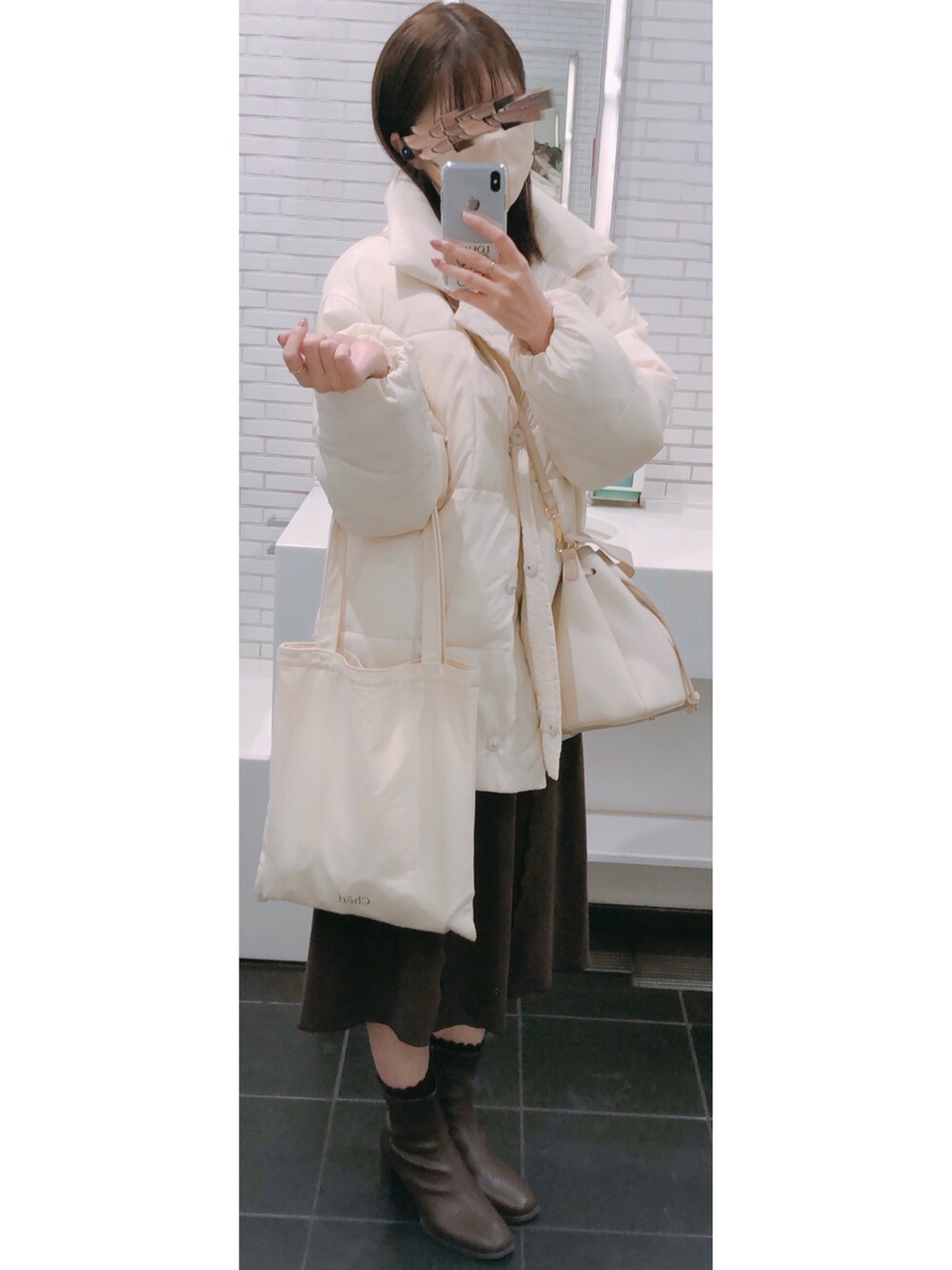 ホワイト系のカーディガン/ボレロ、ブラウン系のワンピース、ゴールド系のネックレスを着用したレディースの冬コーディネートの4枚目の写真