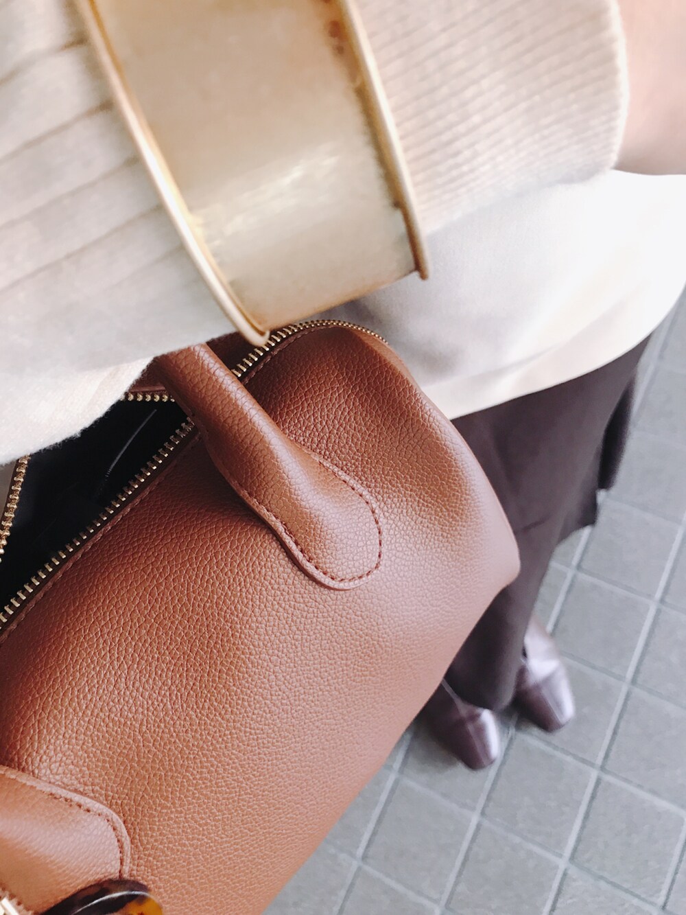 ブラウン系のバッグ、ブラウン系のスカート、ホワイト系のベストを着用したレディースの秋コーディネートの4枚目の写真