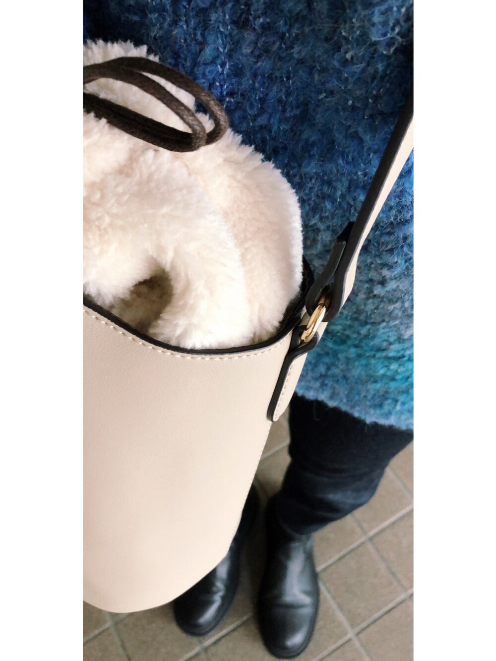 ブルー系のデニムパンツ、ホワイト系のバッグ、ブルー系のニット/セーターを着用したレディースの冬コーディネートの3枚目の写真