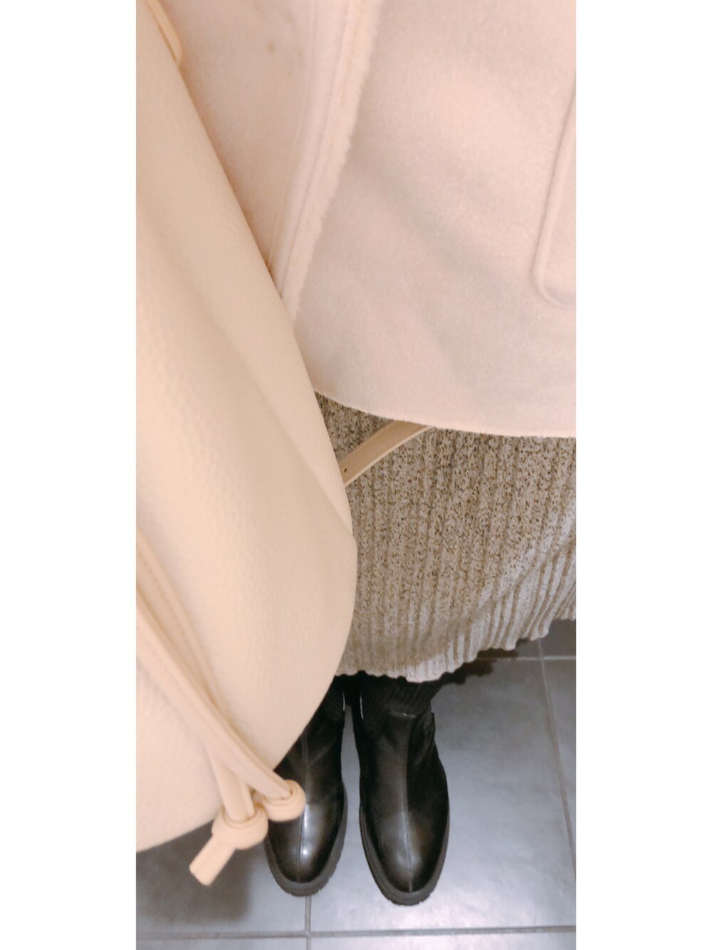 ホワイト系のトップス、ホワイト系のベスト、グレー系のスカートを着用したレディースの冬コーディネートの3枚目の写真