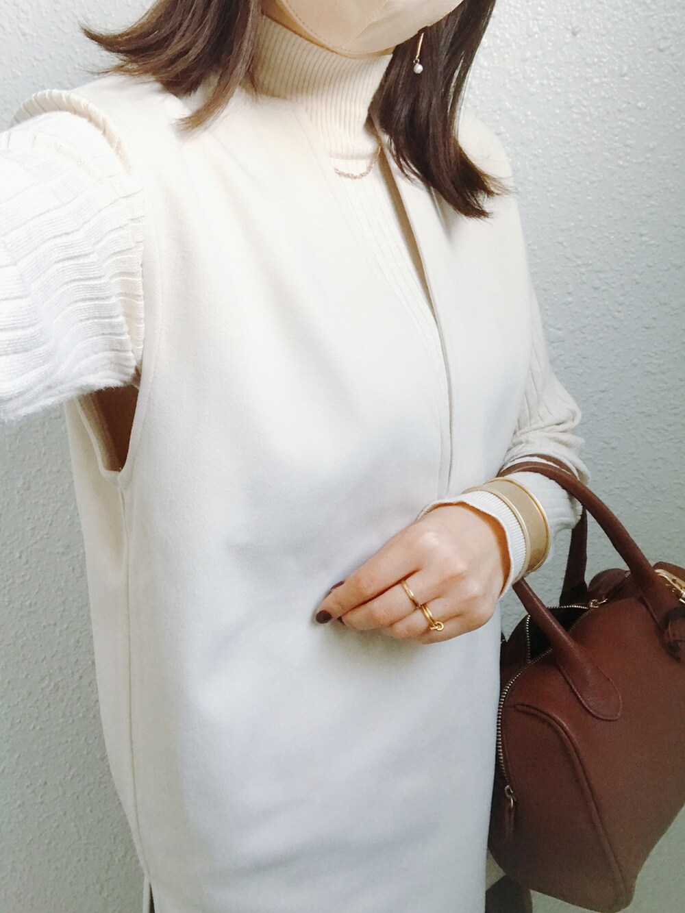 ブラウン系のバッグ、ブラウン系のスカート、ホワイト系のベストを着用したレディースの秋コーディネートの2枚目の写真