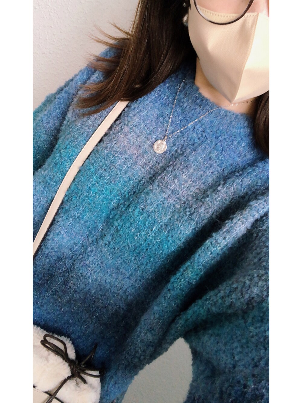 ブルー系のデニムパンツ、ホワイト系のバッグ、ブルー系のニット/セーターを着用したレディースの冬コーディネートの2枚目の写真