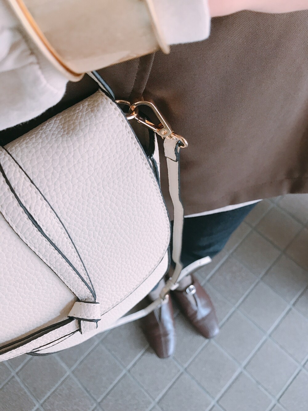 ホワイト系のバッグ、ブラウン系のベスト、ベージュ系のTシャツ/カットソーを着用したレディースの秋コーディネートの3枚目の写真