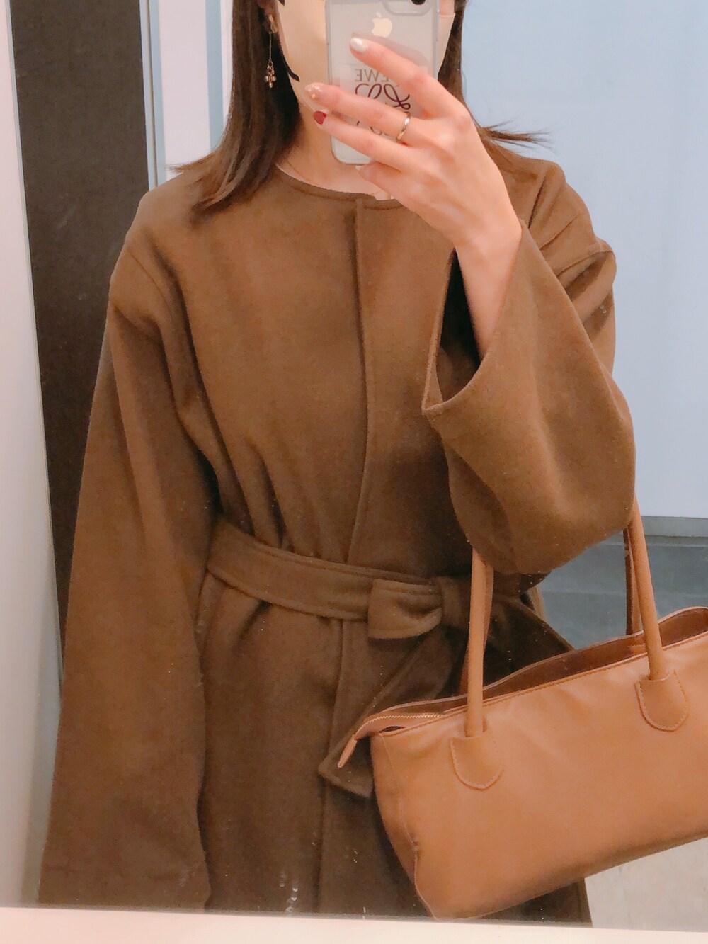 ブラウン系のノーカラーコート、ブラウン系のバッグ、ベージュ系のワンピース/ドレスを着用したレディースの冬コーディネートの3枚目の写真