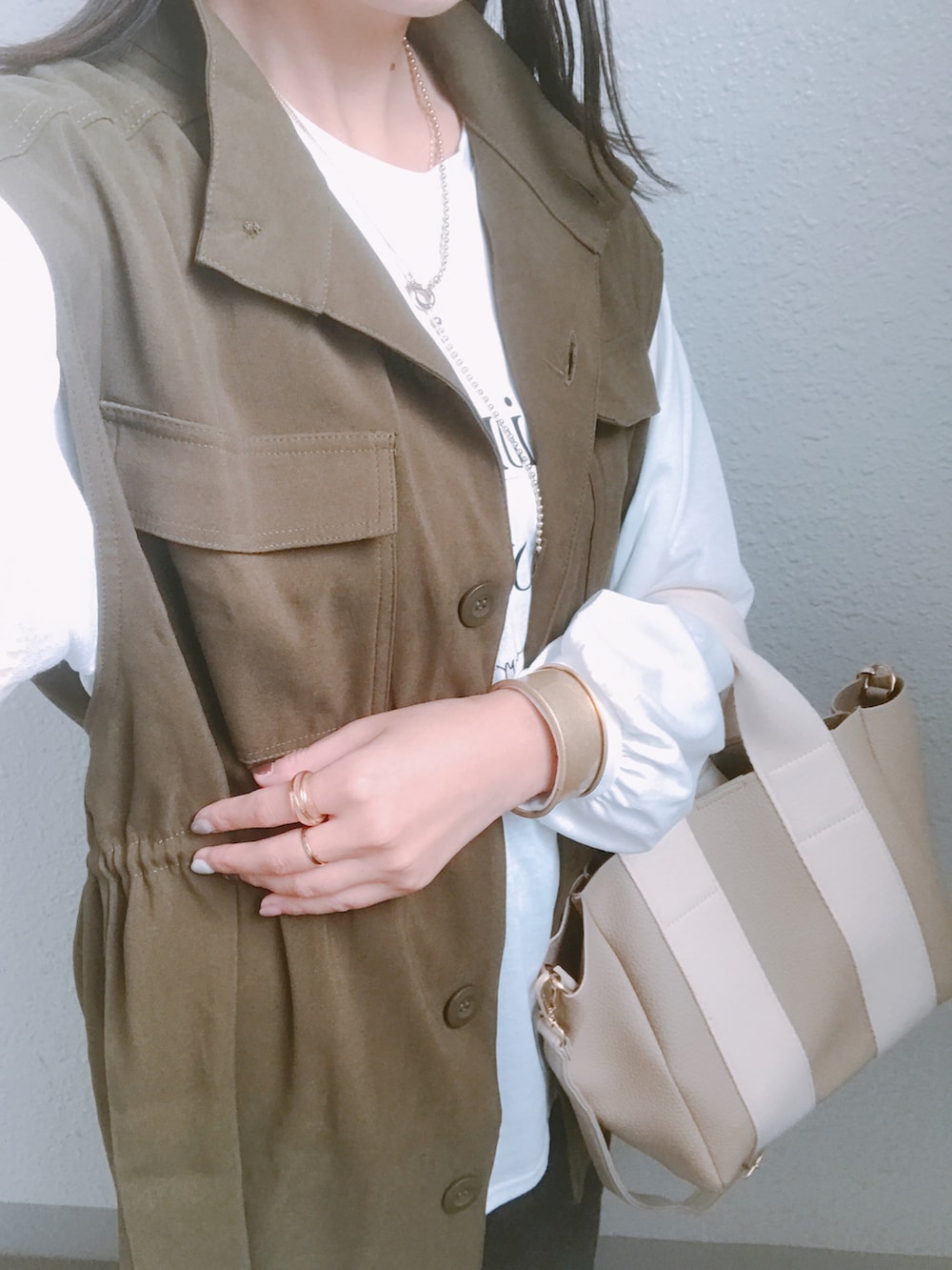 グリーン系のベスト、ホワイト系のTシャツ/カットソー、ゴールド系のネックレスを着用したレディースの秋コーディネートの2枚目の写真