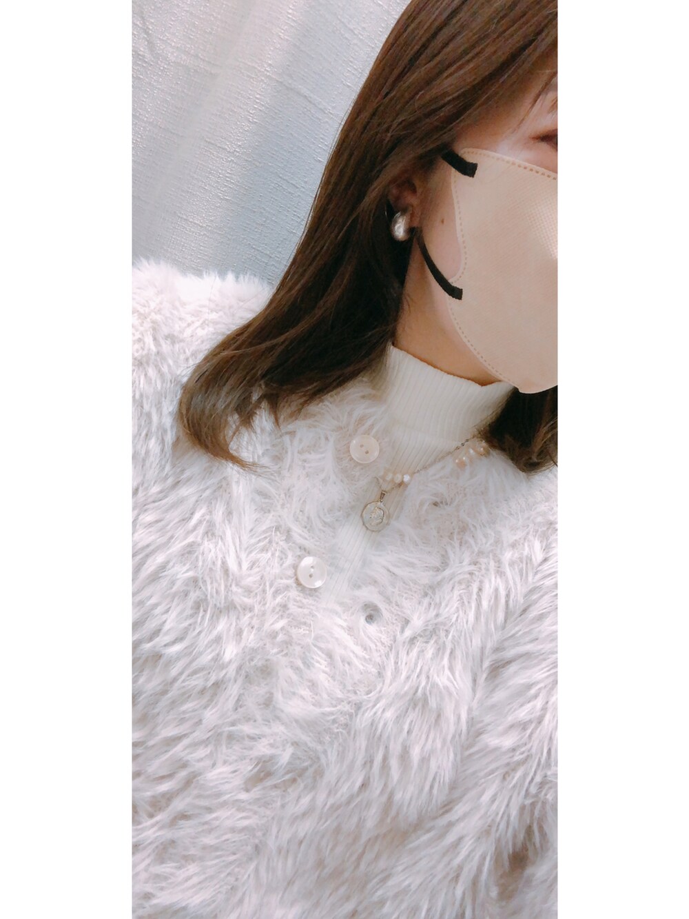 ホワイト系のトップス、ホワイト系のカーディガン/ボレロ、ホワイト系のバッグを着用したレディースの冬コーディネートの4枚目の写真