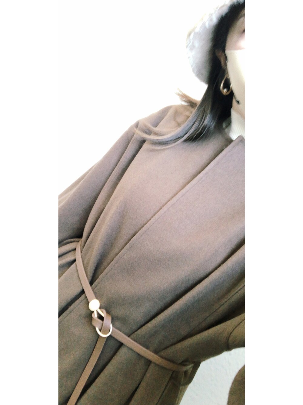 ブラウン系のノーカラーコート、ブラウン系のバッグ、ホワイト系のニット/セーターを着用したレディースの冬コーディネートの2枚目の写真