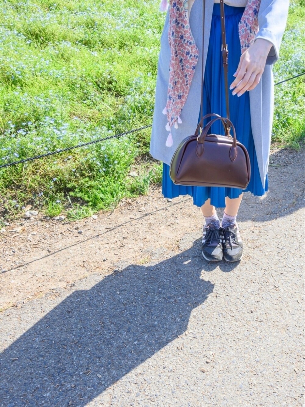 ホワイト系のジャケット/アウター、ブルー系のスカート、ブラウン系のボストンバッグを着用したレディースの春コーディネートの2枚目の写真