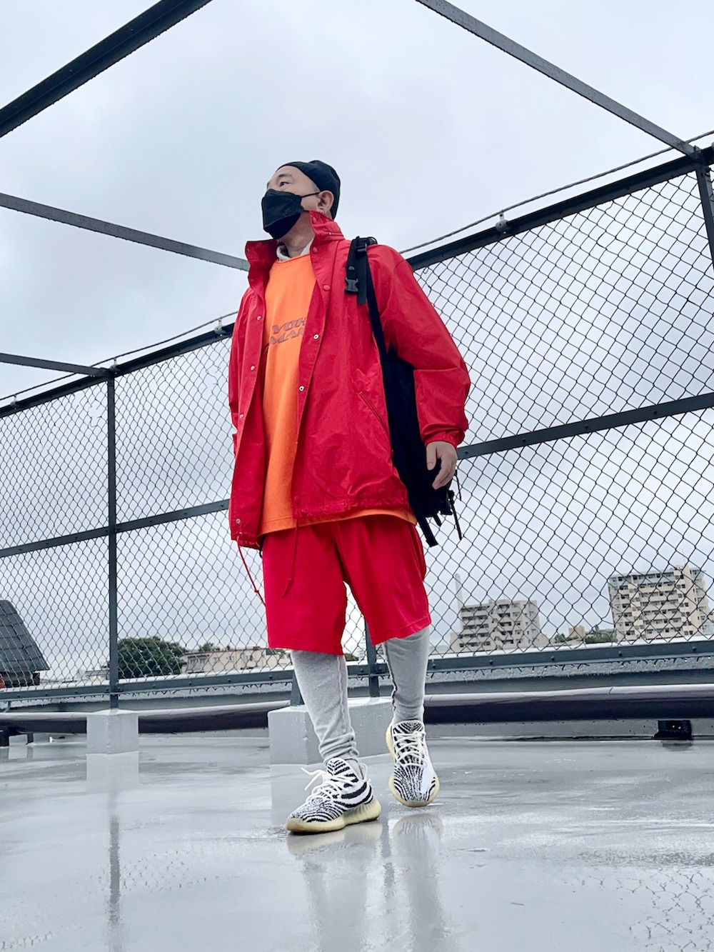 レッド系のナイロンジャケット、レッド系のその他パンツ、ホワイト系のスニーカーを着用したメンズの秋コーディネートの2枚目の写真