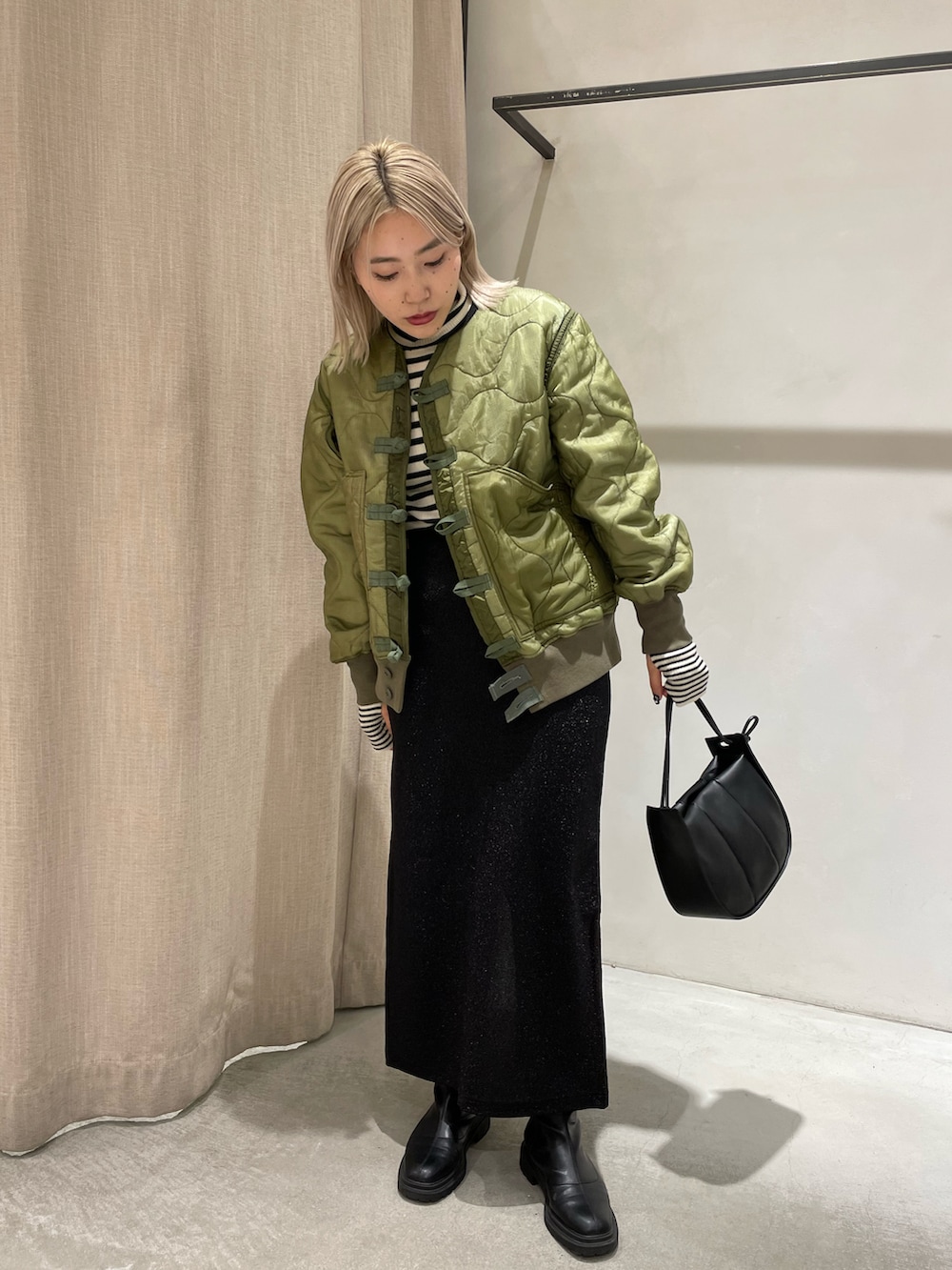 ブラック系のブーツ、ブラック系のスカート、ブラック系のショルダーバッグを着用したレディースの冬コーディネートの2枚目の写真