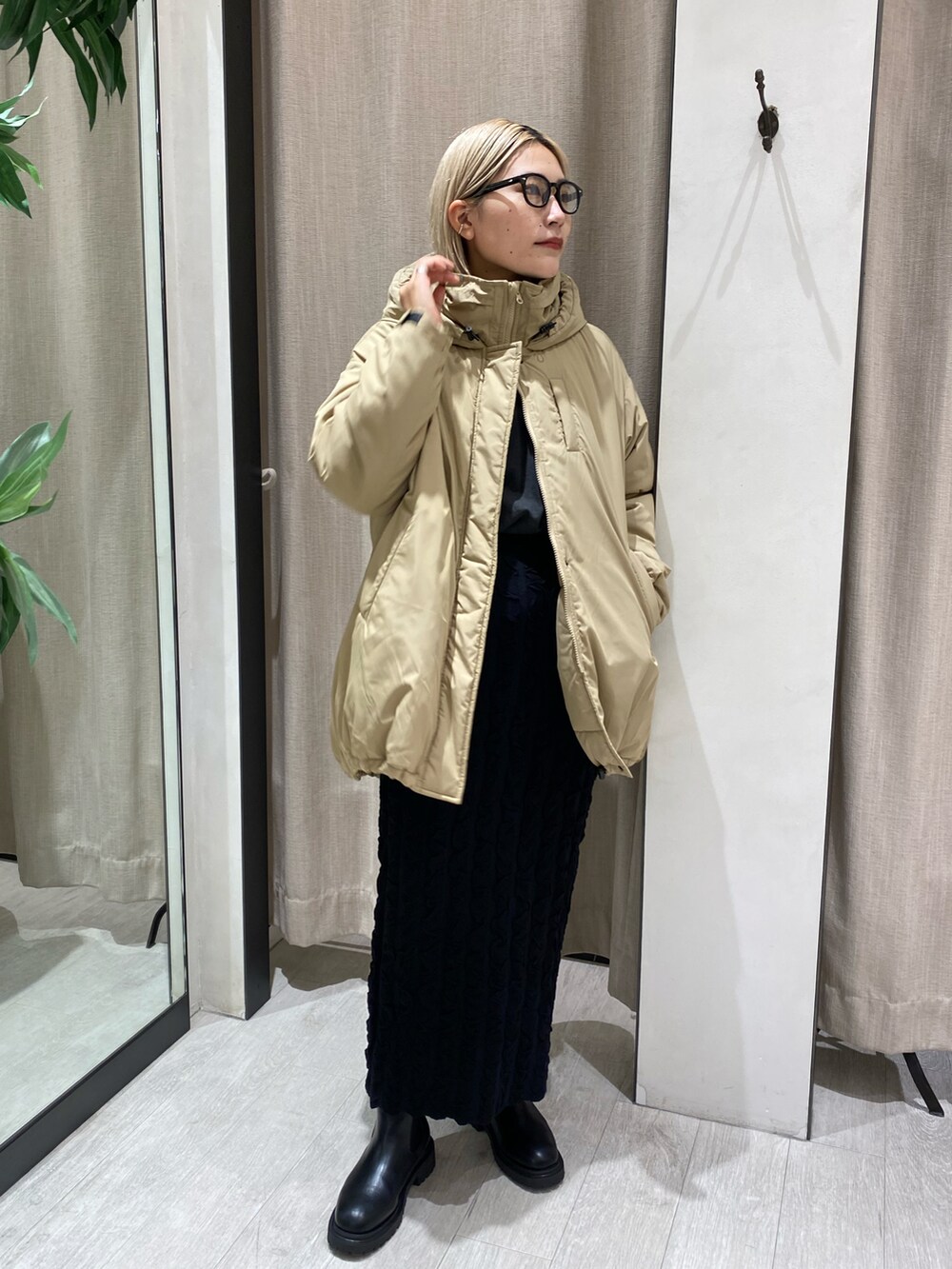 ベージュ系のダウンジャケット/コート、ブラック系のスカート、ブラック系のブーツを着用したレディースの秋コーディネートの2枚目の写真