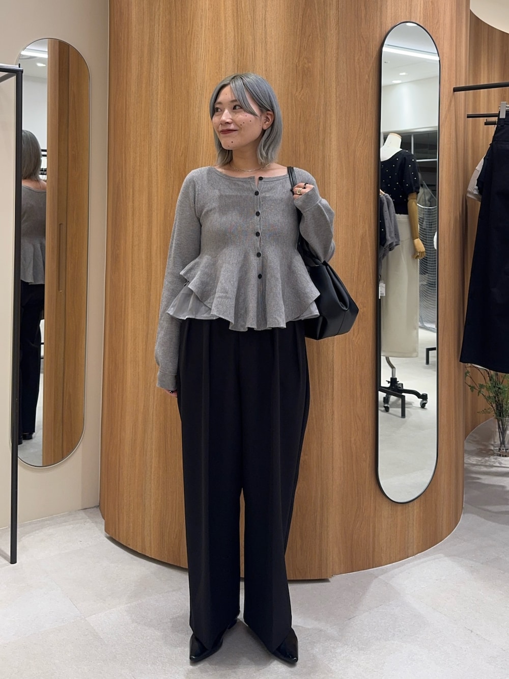 ブラック系のその他パンツ、ブラック系のトートバッグ、グレー系のニット/セーターを着用したレディースの秋コーディネートの2枚目の写真