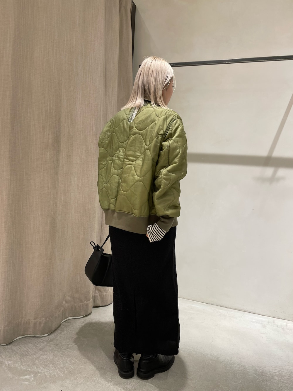 ブラック系のブーツ、ブラック系のスカート、ブラック系のショルダーバッグを着用したレディースの冬コーディネートの3枚目の写真