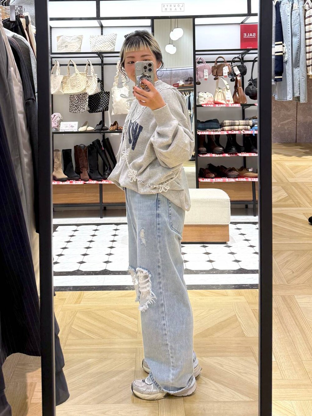 ブルー系のデニムパンツ、グレー系のスウェット、ベージュ系のスマホグッズを着用したレディースの冬コーディネートの4枚目の写真