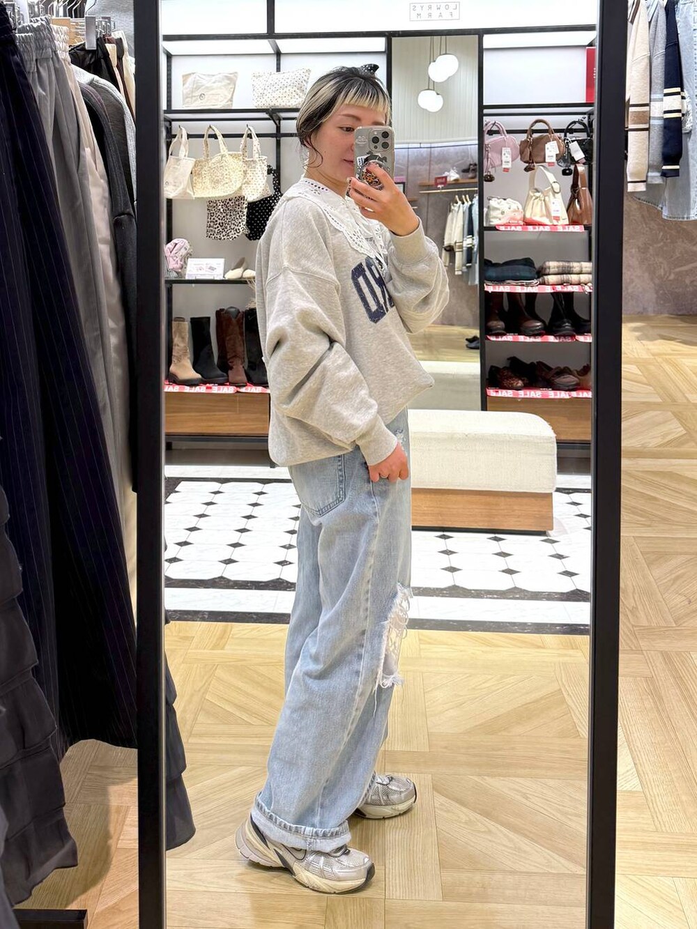 ブルー系のデニムパンツ、グレー系のスウェット、ベージュ系のスマホグッズを着用したレディースの冬コーディネートの5枚目の写真