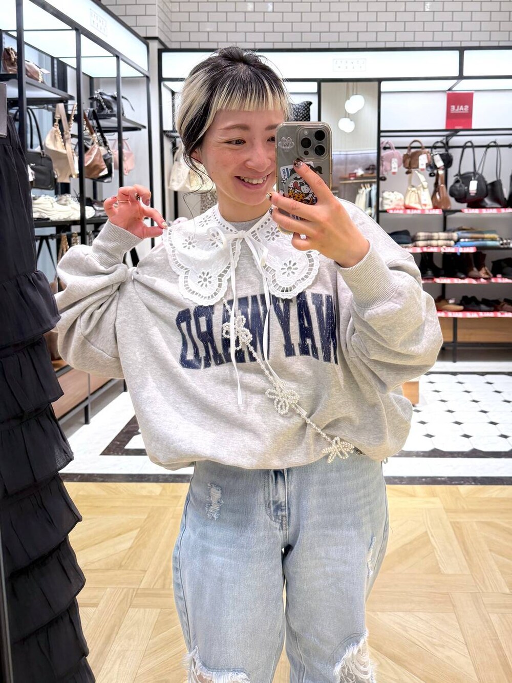 ブルー系のデニムパンツ、グレー系のスウェット、ベージュ系のスマホグッズを着用したレディースの冬コーディネートの3枚目の写真