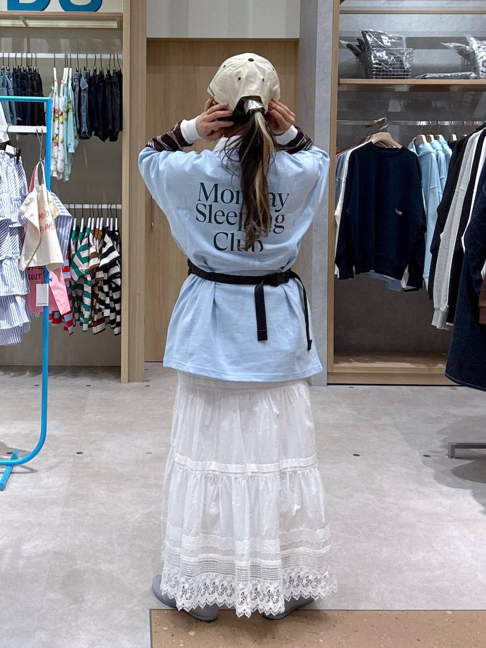 ブルー系のスニーカー、ブラック系のボディバッグ/ウエストポーチ、ブラウン系のポロシャツを着用したレディースの春コーディネートの3枚目の写真