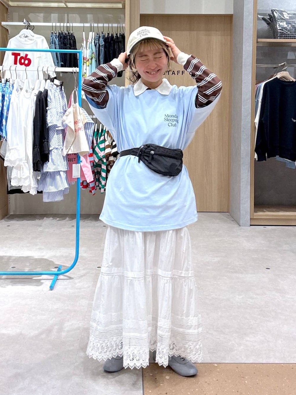 ブルー系のスニーカー、ブラック系のボディバッグ/ウエストポーチ、ブラウン系のポロシャツを着用したレディースの春コーディネートの2枚目の写真