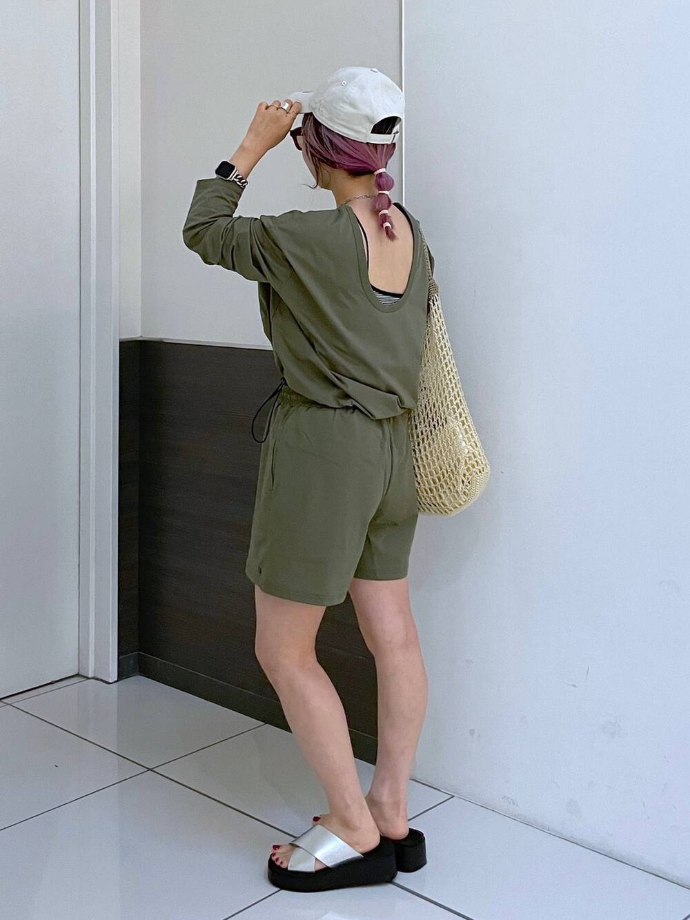 ベージュ系のショルダーバッグ、シルバー系のサンダル、グリーン系のラッシュガードを着用したレディースの夏コーディネートの2枚目の写真