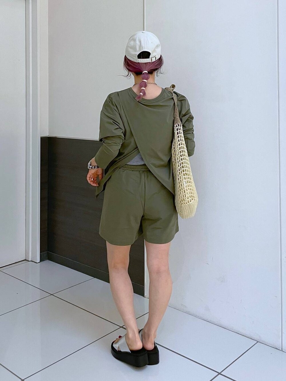 ベージュ系のショルダーバッグ、シルバー系のサンダル、グリーン系のラッシュガードを着用したレディースの夏コーディネートの3枚目の写真