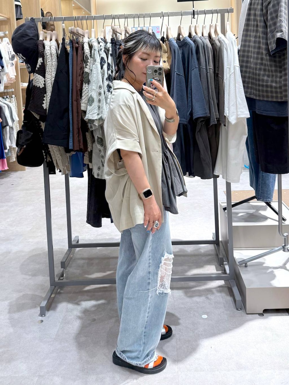 ブルー系のデニムパンツ、ホワイト系のテーラードジャケット、シルバー系のサンダルを着用したレディースの夏コーディネートの4枚目の写真