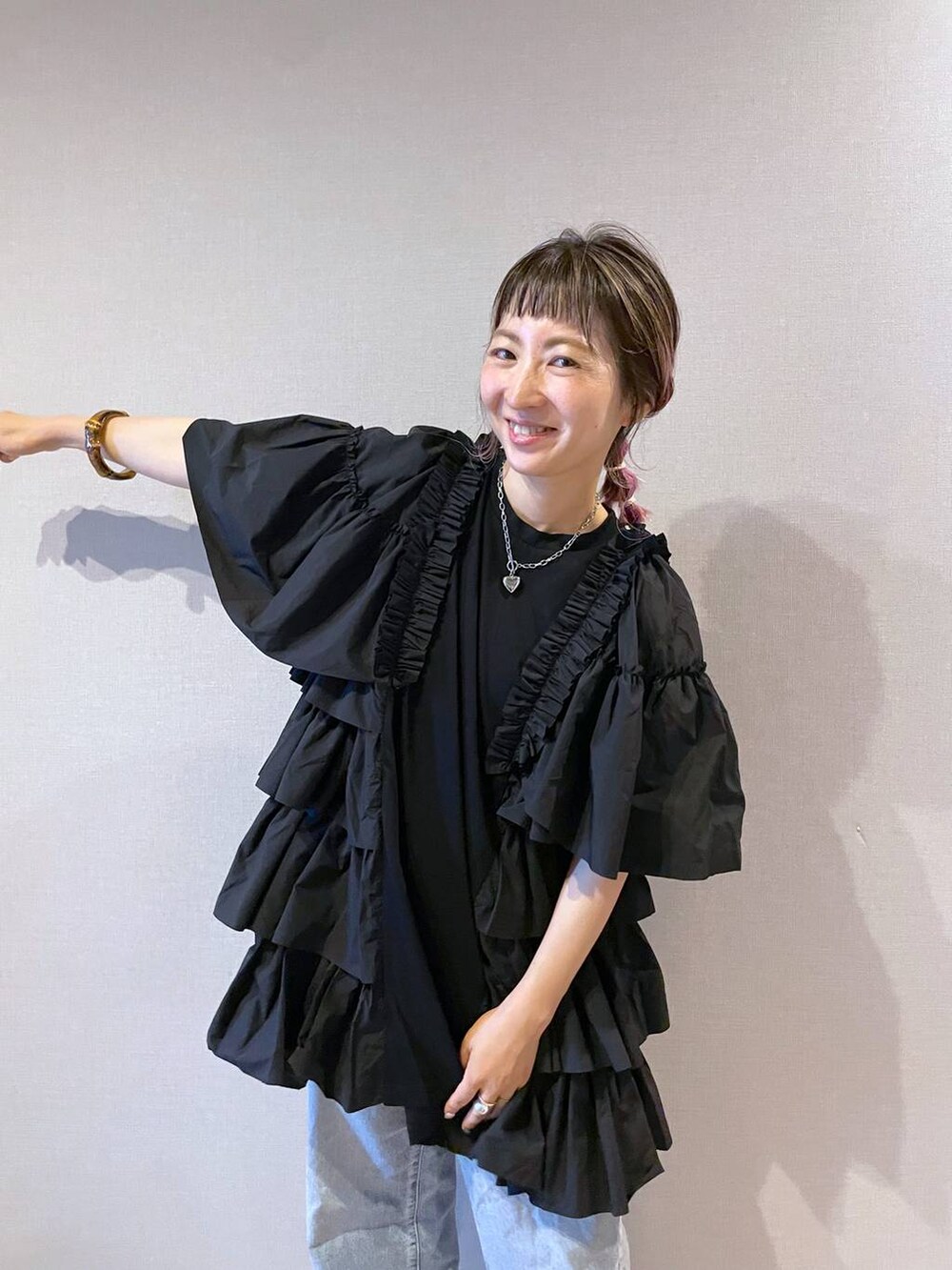 ブラック系のチュニック、グレー系のネックレスを着用したレディースの夏コーディネートの2枚目の写真