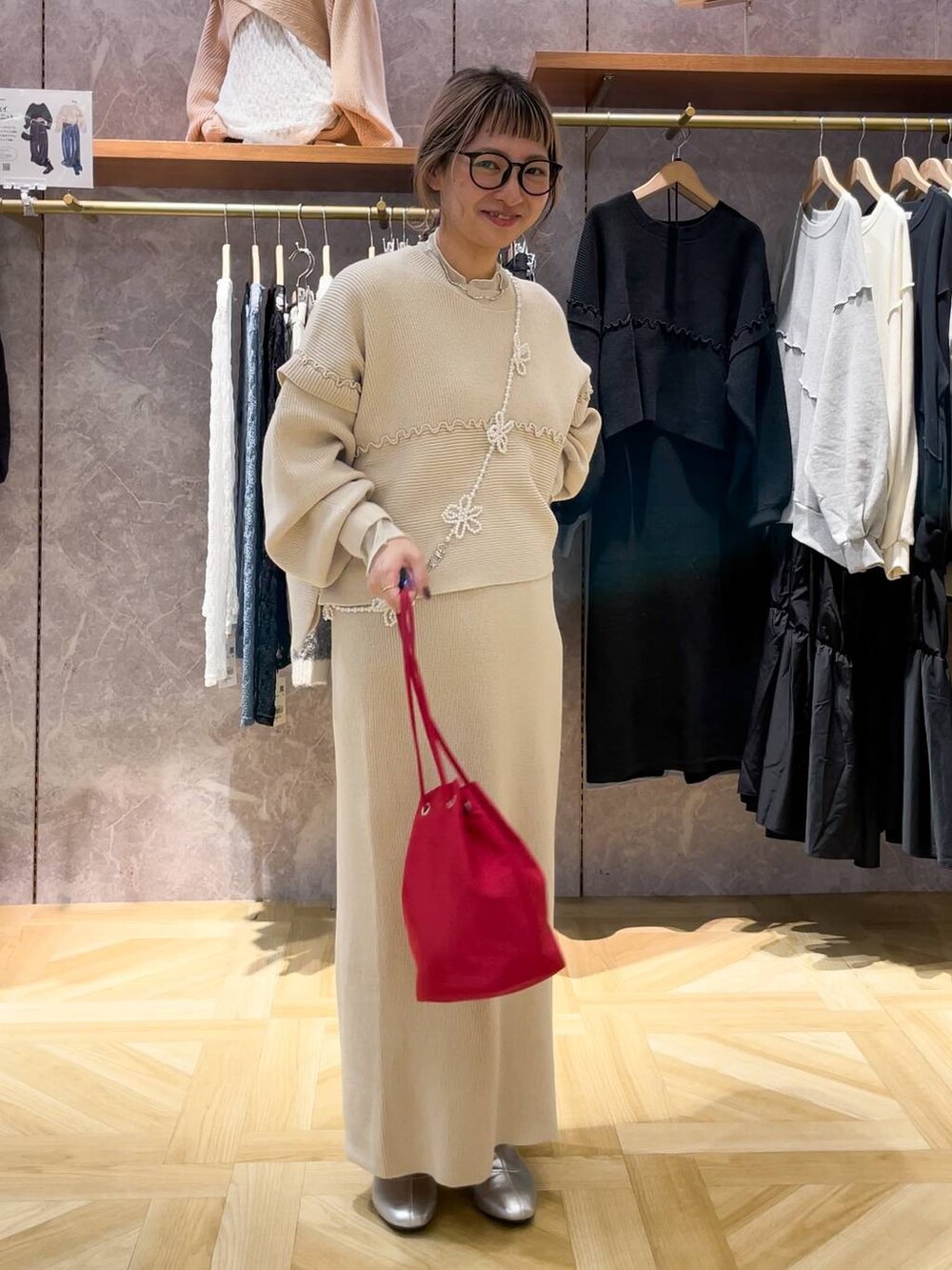 シルバー系のブーツ、レッド系のハンドバッグ、ベージュ系のワンピースを着用したレディースの秋コーディネートの2枚目の写真