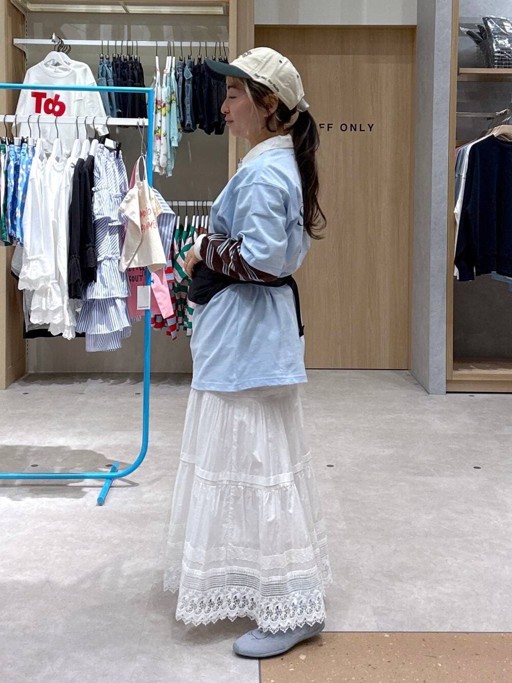 ブルー系のスニーカー、ブラック系のボディバッグ/ウエストポーチ、ブラウン系のポロシャツを着用したレディースの春コーディネートの4枚目の写真