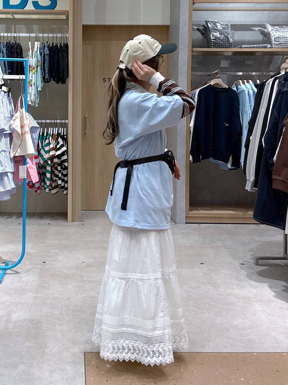 ブルー系のスニーカー、ブラック系のボディバッグ/ウエストポーチ、ブラウン系のポロシャツを着用したレディースの春コーディネートの5枚目の写真