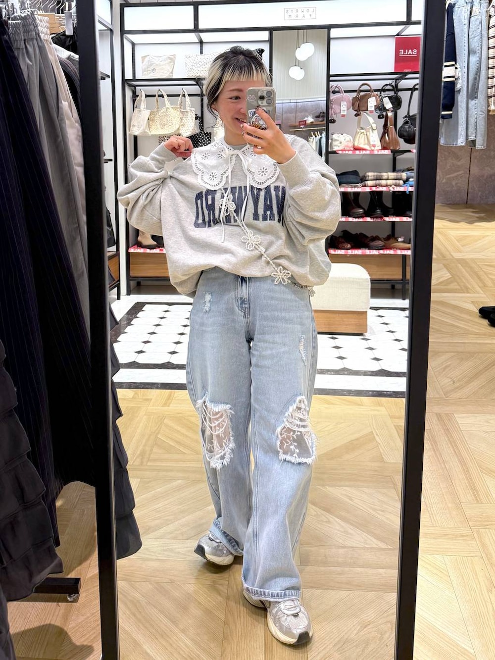 ブルー系のデニムパンツ、グレー系のスウェット、ベージュ系のスマホグッズを着用したレディースの冬コーディネートの2枚目の写真