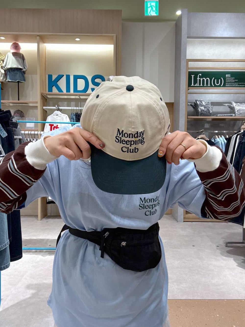 ブルー系のスニーカー、ブラック系のボディバッグ/ウエストポーチ、ブラウン系のポロシャツを着用したレディースの春コーディネートの6枚目の写真