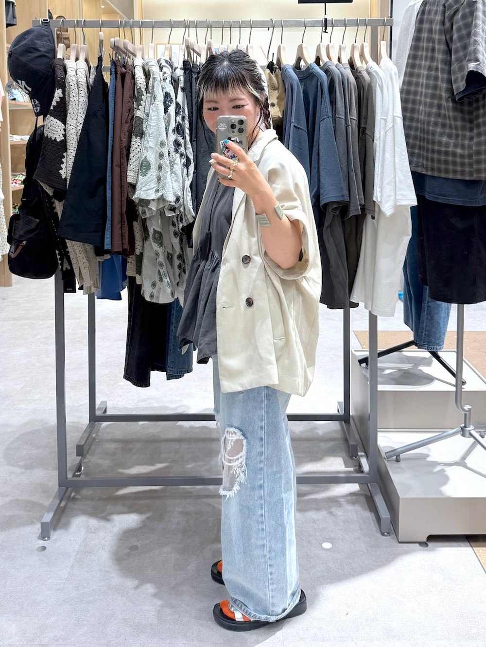 ブルー系のデニムパンツ、ホワイト系のテーラードジャケット、シルバー系のサンダルを着用したレディースの夏コーディネートの3枚目の写真