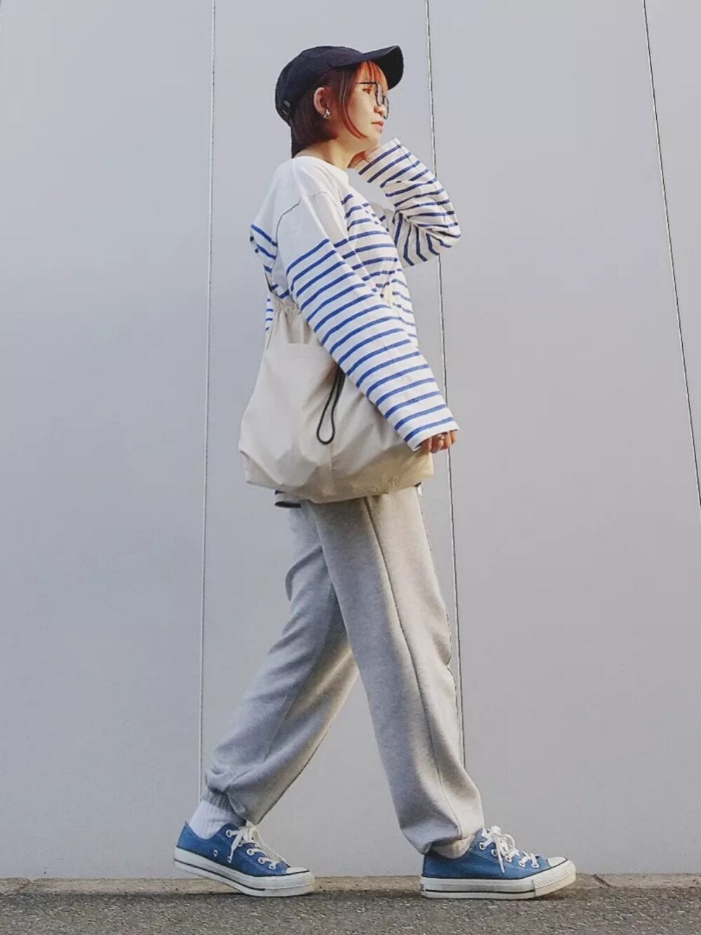 ホワイト系のTシャツ/カットソー、グレー系のスウェットパンツ、ブルー系のスニーカーを着用したレディースの春コーディネートの4枚目の写真