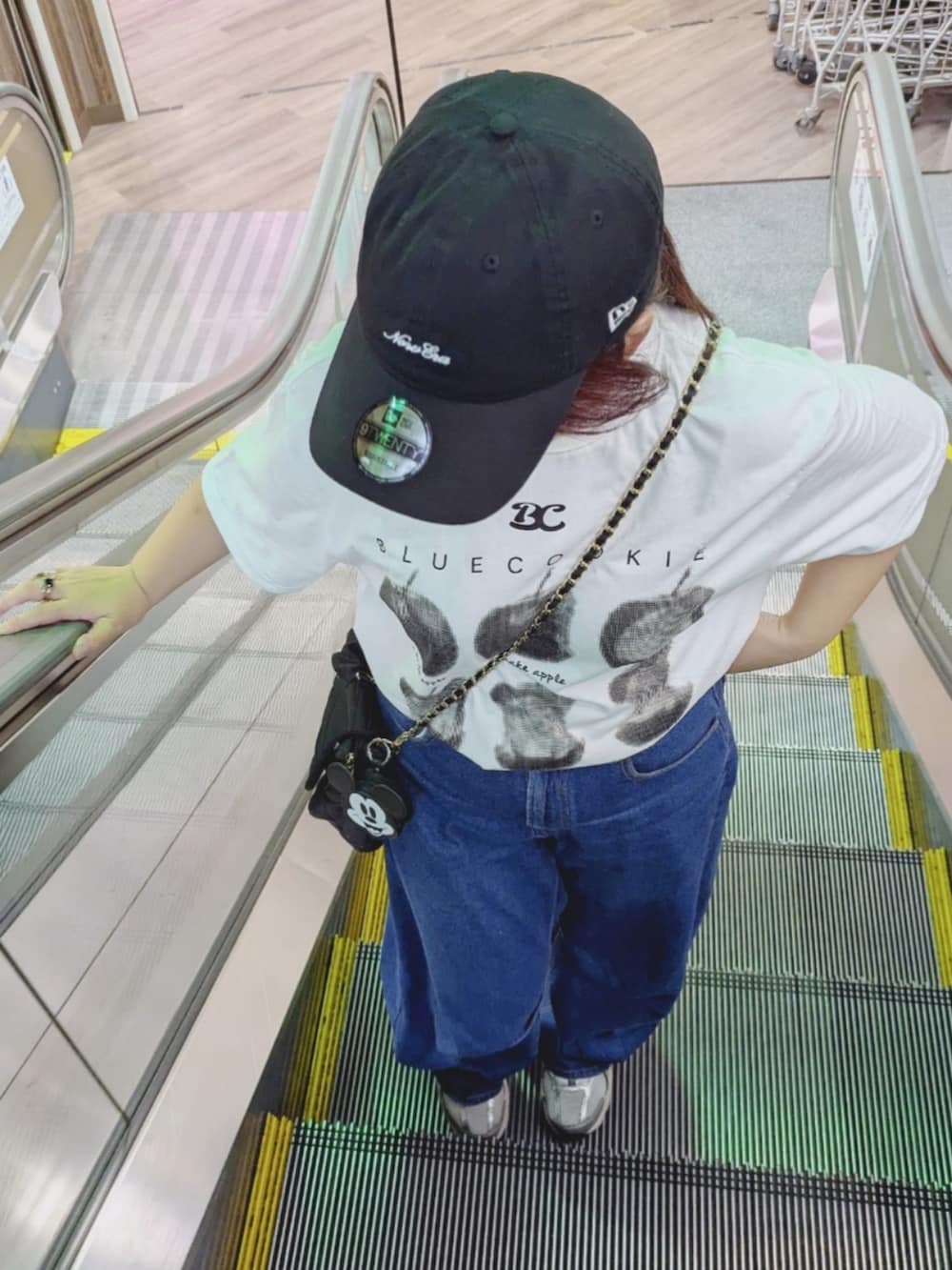 ブルー系のデニムパンツ、ブラック系のショルダーバッグ、シルバー系のスニーカーを着用したレディースの夏コーディネートの2枚目の写真