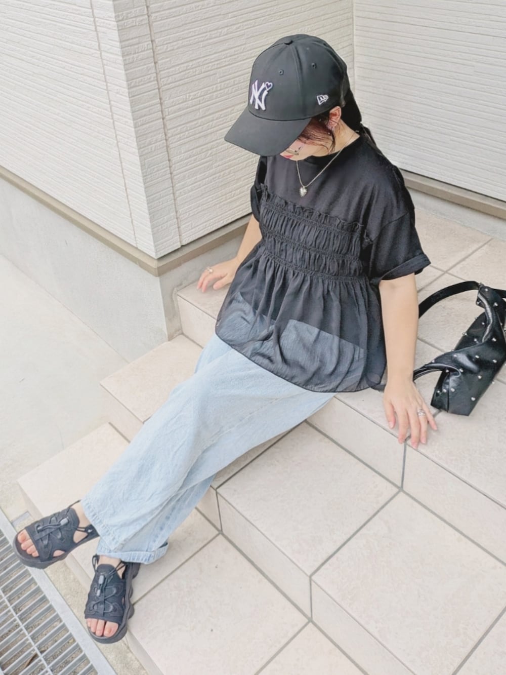 ブラック系のTシャツ/カットソー、ブルー系のデニムパンツ、ブラック系のサンダルを着用したレディースの夏コーディネートの2枚目の写真