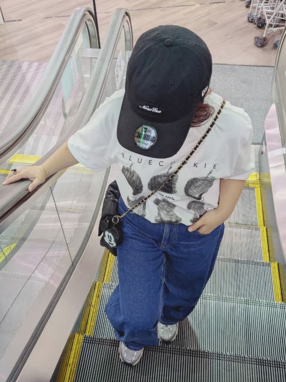 ブルー系のデニムパンツ、ブラック系のショルダーバッグ、シルバー系のスニーカーを着用したレディースの夏コーディネートの3枚目の写真