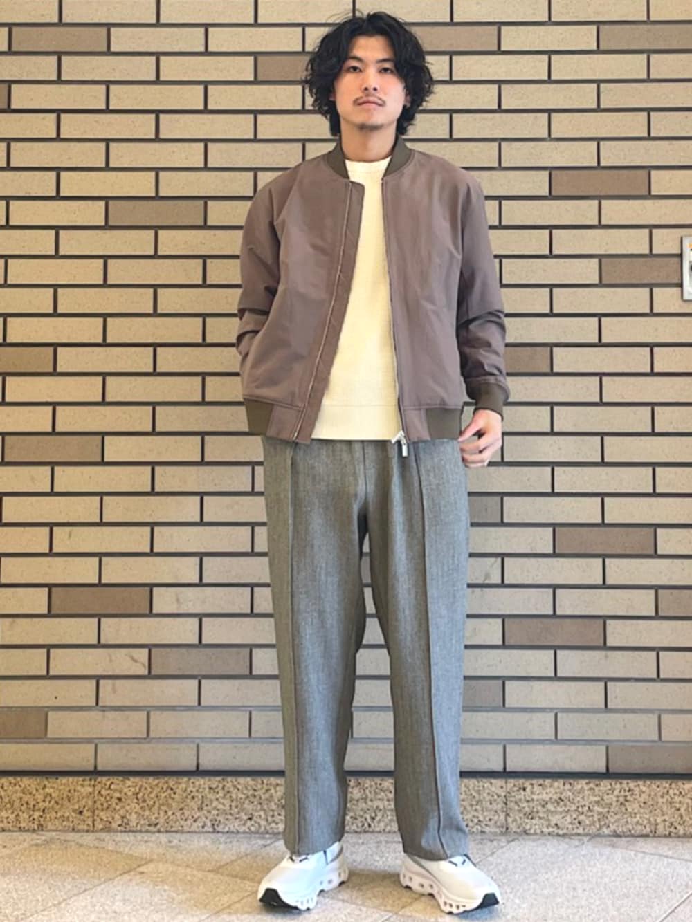 イエロー系のブルゾン、グレー系のスラックス、ベージュ系のスウェットを着用したメンズの秋コーディネートの2枚目の写真