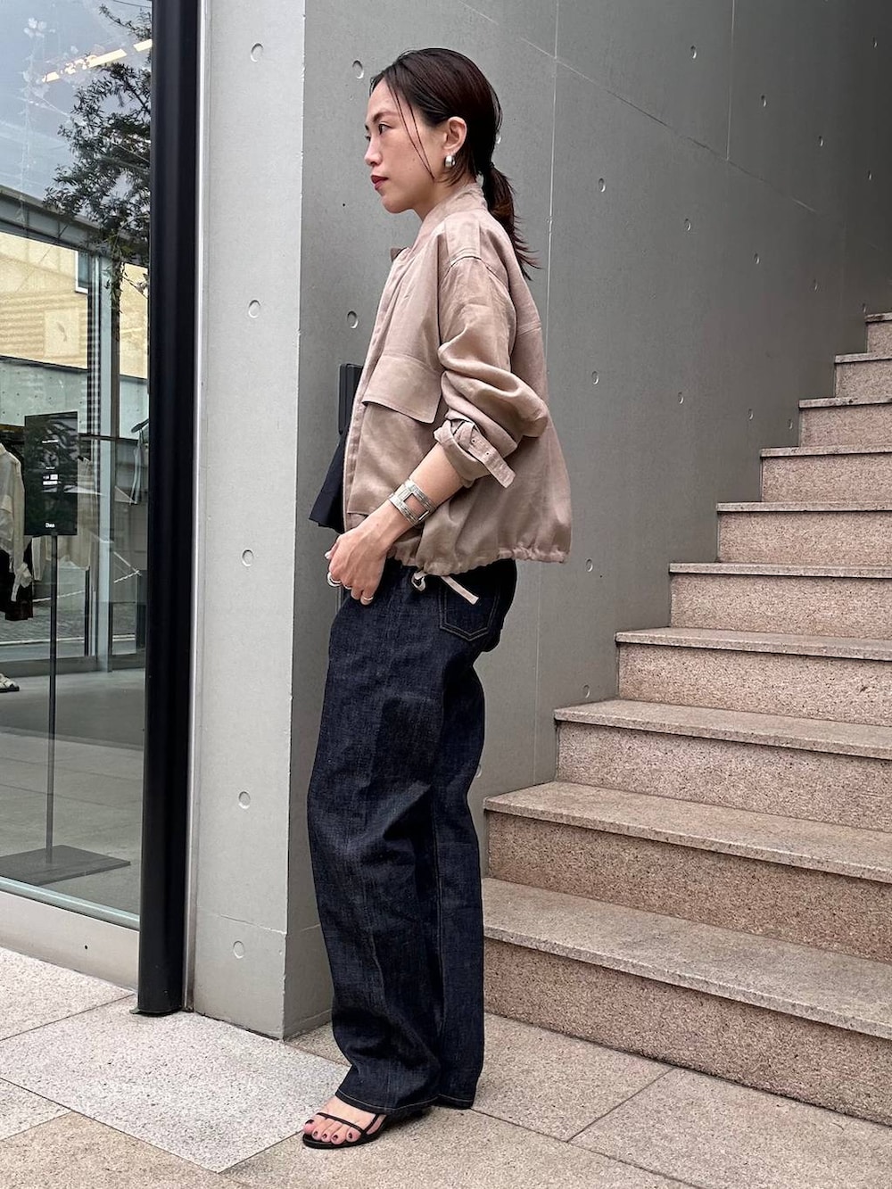 ブラウン系のブルゾン、ブルー系のデニムパンツ、ブラック系のシャツ/ブラウスを着用したレディースの春コーディネートの2枚目の写真