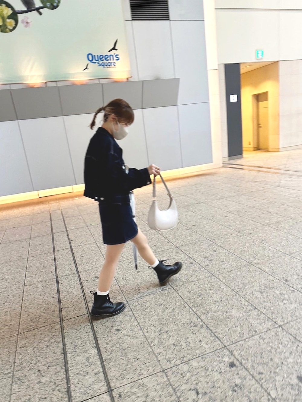 ブルー系のデニムジャケット、ホワイト系のハンドバッグ、ブラック系のブーツを着用したレディースの春コーディネートの2枚目の写真