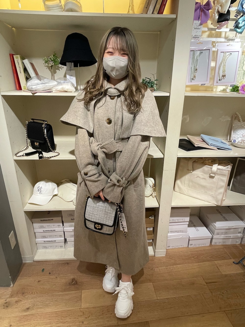 ブラウン系のステンカラーコート、ホワイト系のスニーカー、ホワイト系のショルダーバッグを着用したレディースの夏コーディネートの2枚目の写真