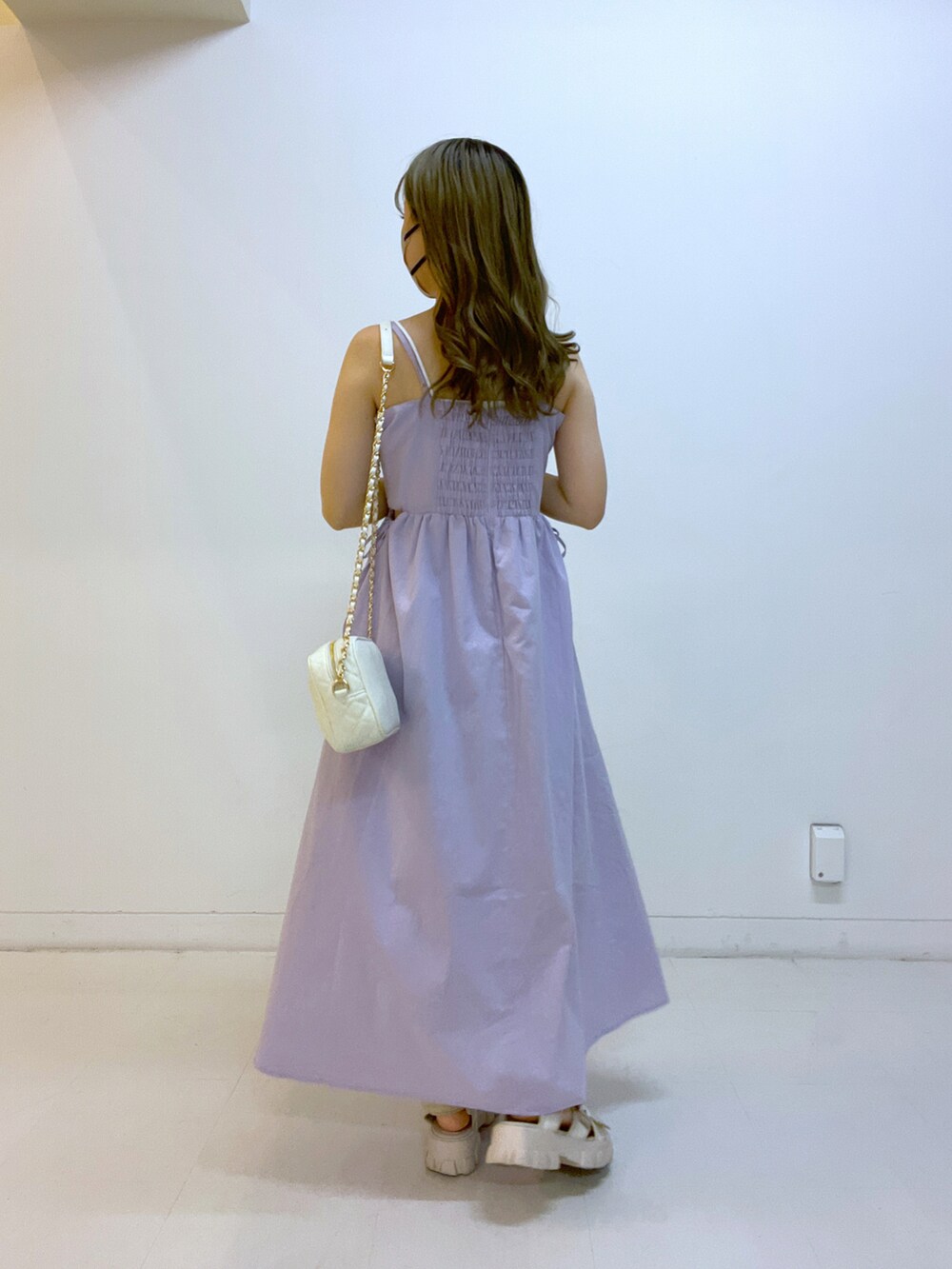パープル系のワンピース、ホワイト系のショルダーバッグを着用したレディースの夏コーディネートの2枚目の写真