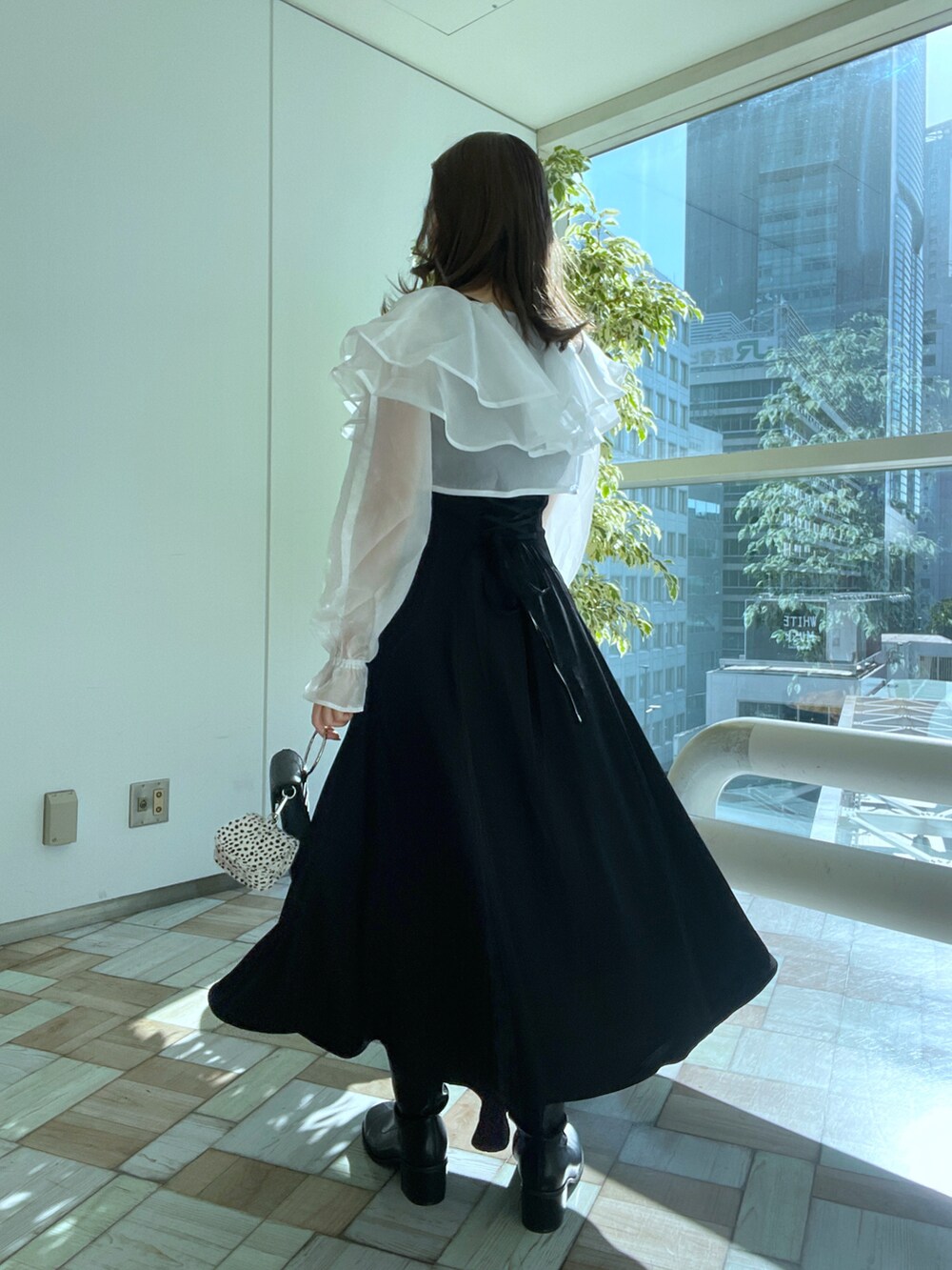 ブラック系のワンピース、ベージュ系のショルダーバッグ、ブラック系のブーツを着用したレディースの冬コーディネートの2枚目の写真