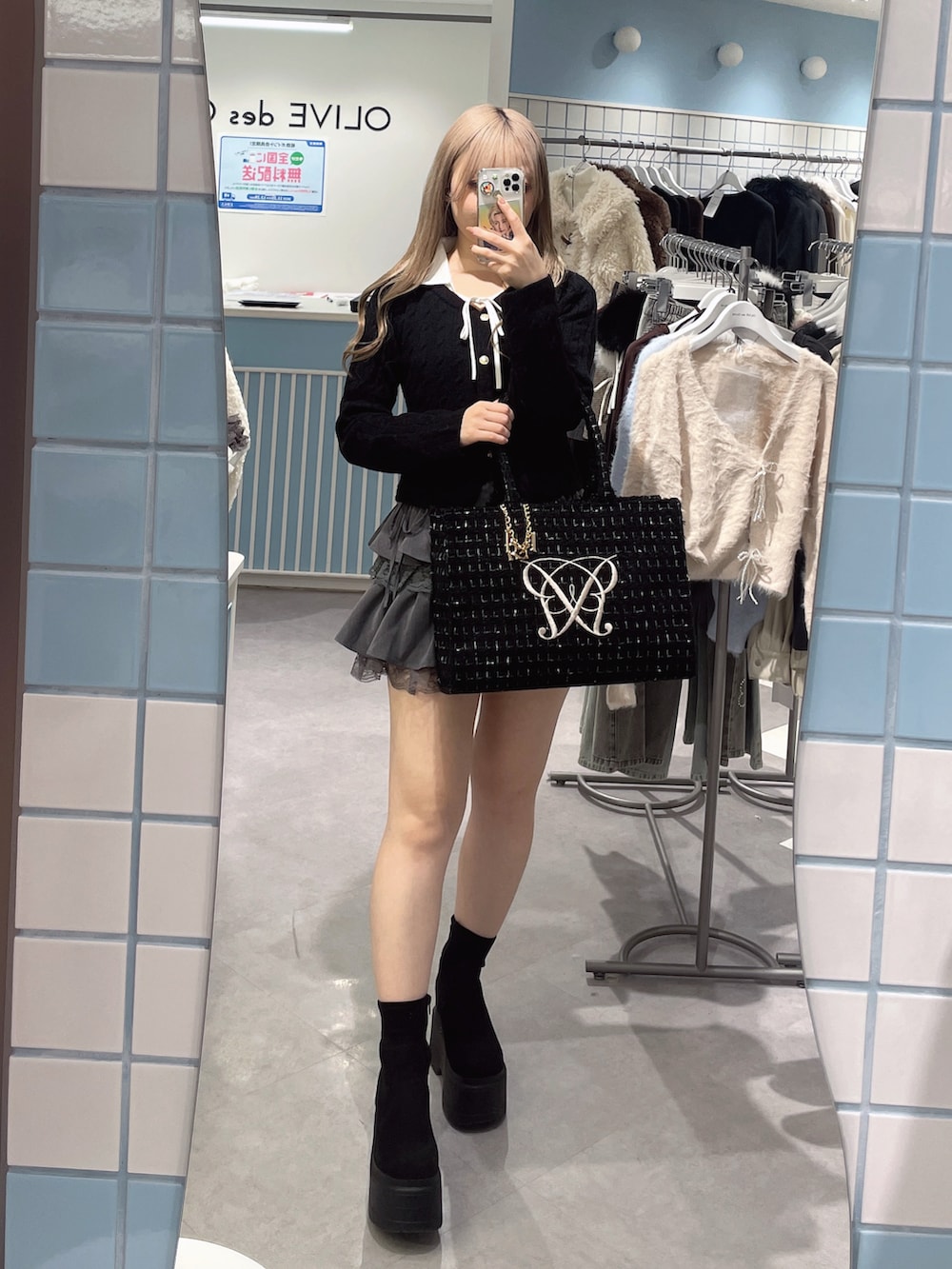 ブラック系のトートバッグ、グレー系のスカート、ブラック系のニット/セーターを着用したレディースの冬コーディネートの2枚目の写真