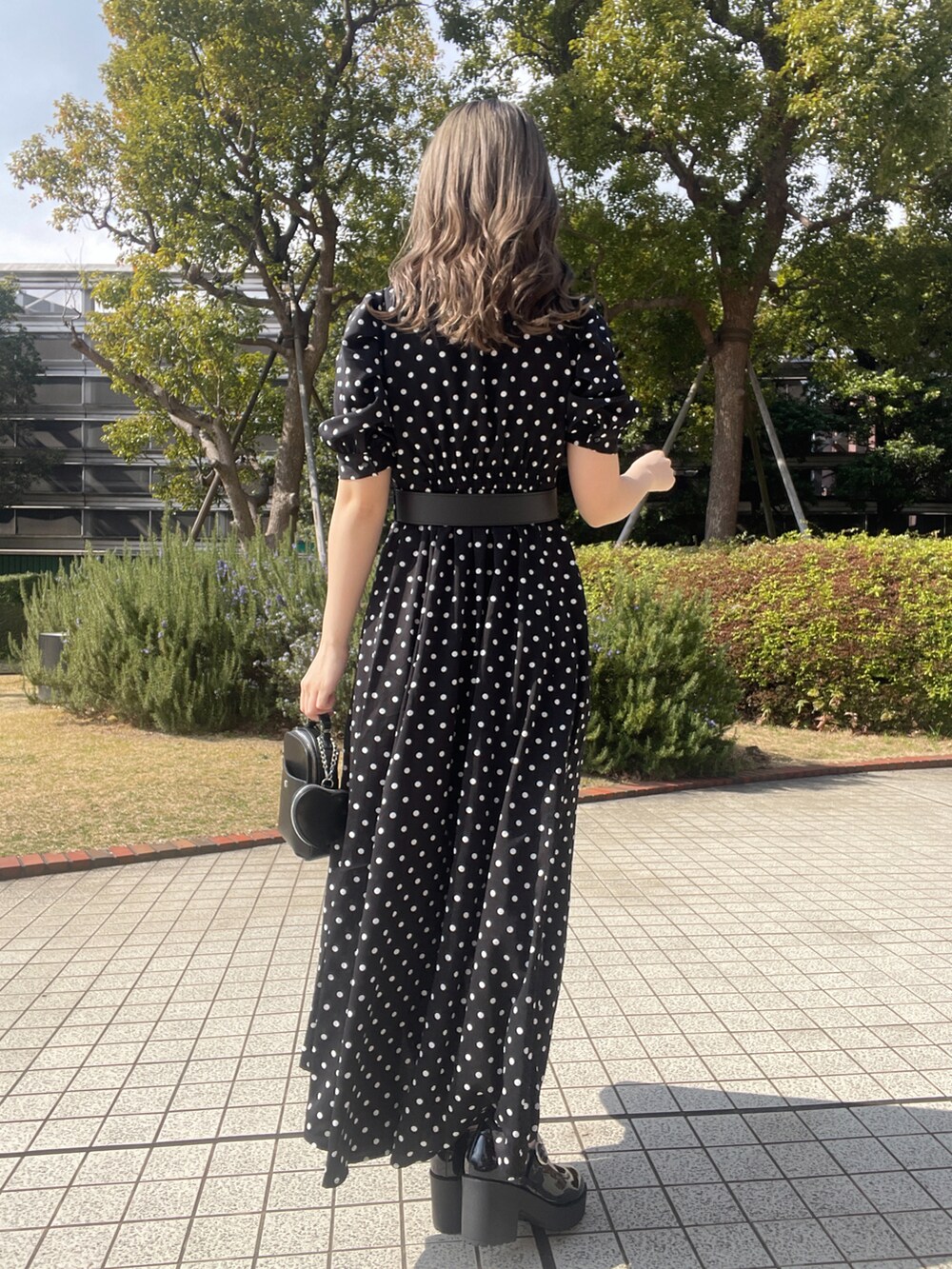 ブラック系のパンプス、ブラック系のショルダーバッグを着用したレディースの春コーディネートの2枚目の写真