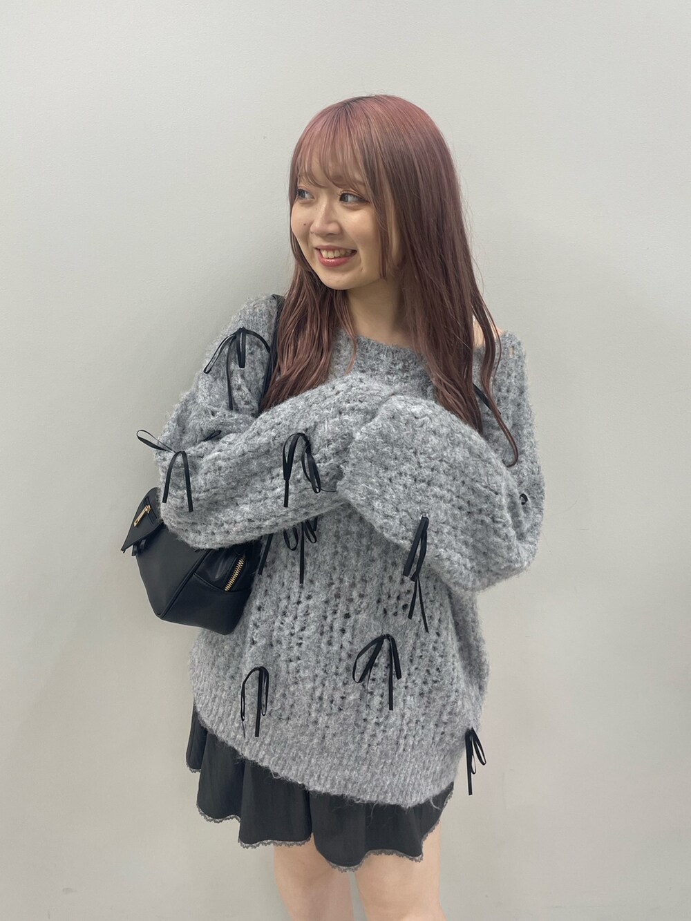 グレー系のニット/セーター、グレー系のスカート、ブラック系のブーツを着用したレディースの秋コーディネートの2枚目の写真