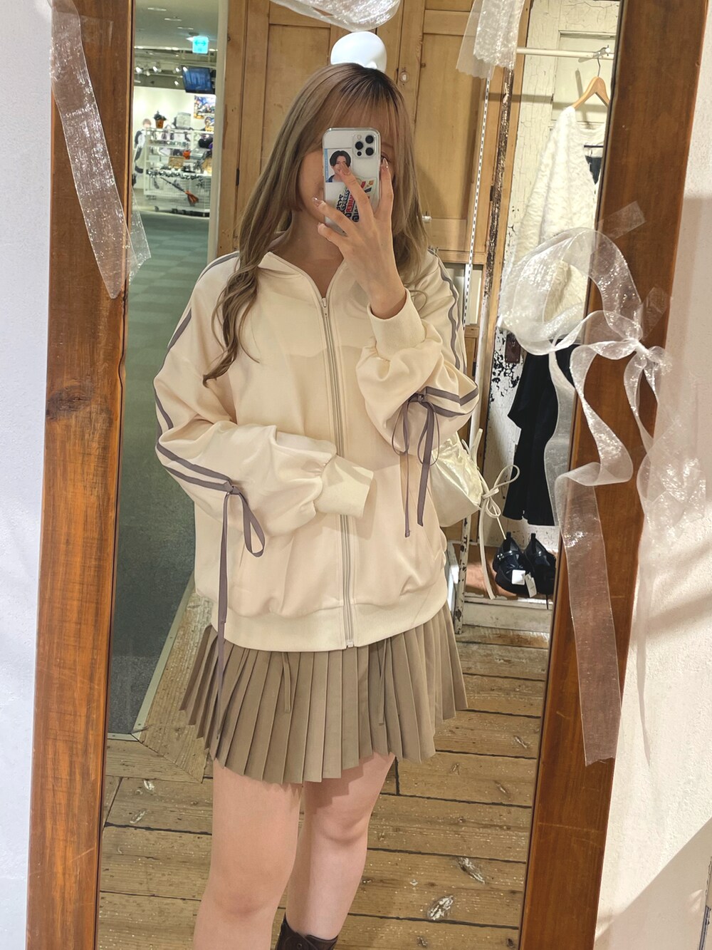 ホワイト系のジャージ、ベージュ系のスカート、ブラウン系のブーツを着用したレディースの秋コーディネートの2枚目の写真