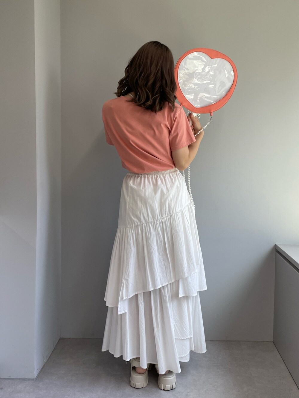 ホワイト系のサンダル、ホワイト系のスカート、オレンジ系のTシャツ/カットソーを着用したレディースの夏コーディネートの2枚目の写真