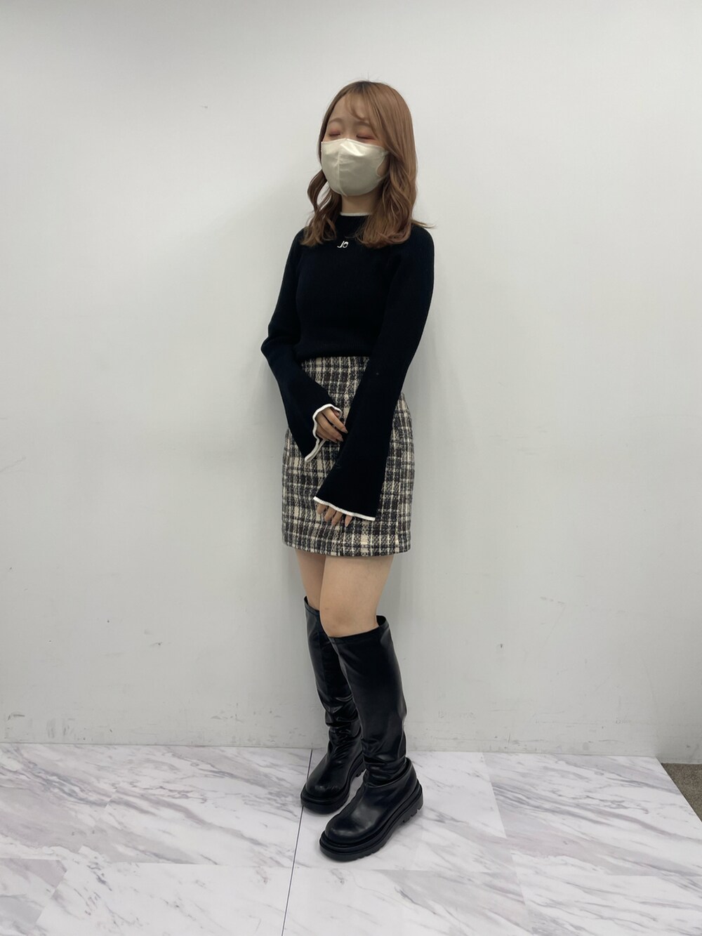 ベージュ系のスカート、ブラック系のニット/セーター、ブラック系のブーツを着用したレディースの秋コーディネートの3枚目の写真